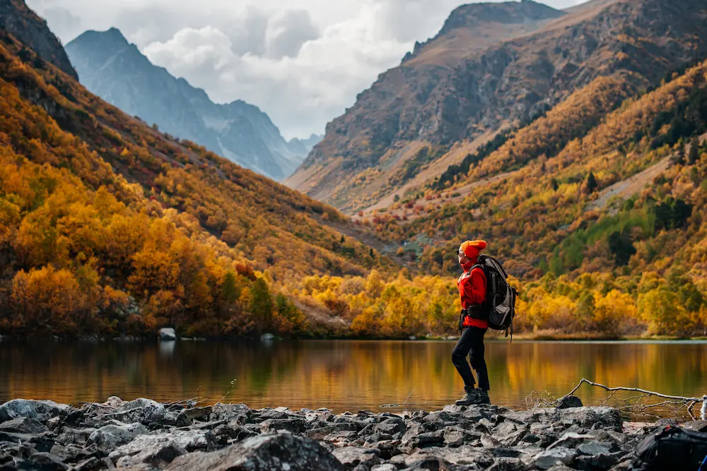 Eine Frau steht vor einem See und wunderschöner herbstlicher Kulisse