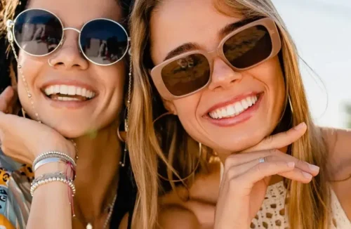 Zwei junge Frauen mit Sonnenbrillen und sommerlicher Kleidung