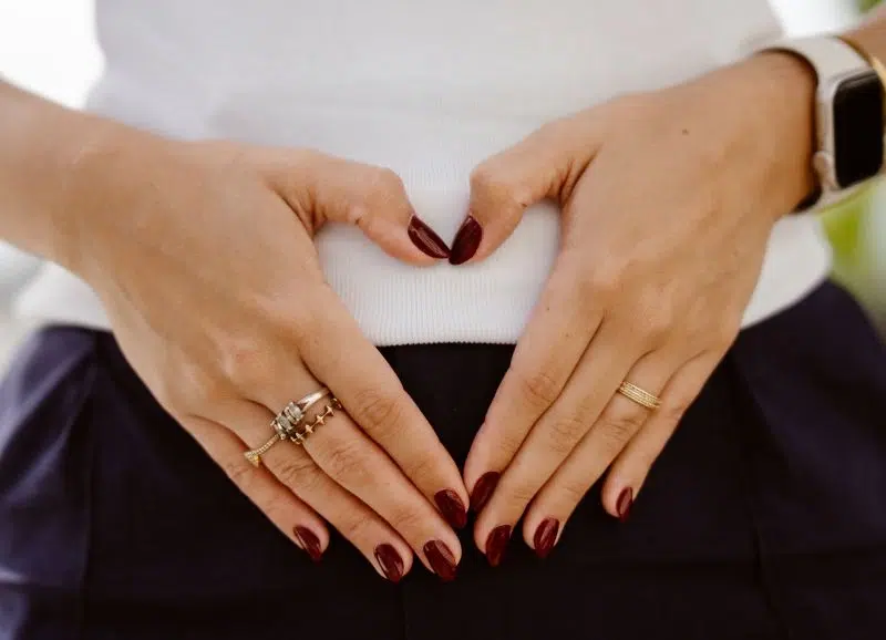 Eine Frau formt mit ihren Händen ein Herz auf ihrem Bauch