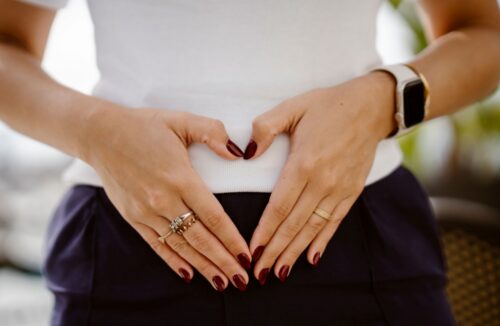 Eine Frau formt mit ihren Händen ein Herz auf ihrem Bauch
