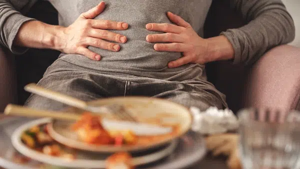 Frau hält ihren Bauch nach einem deftigen Essen