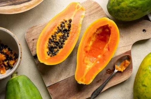 Eine Papaya liegt aufgeschnitten auf einem Holzbrett