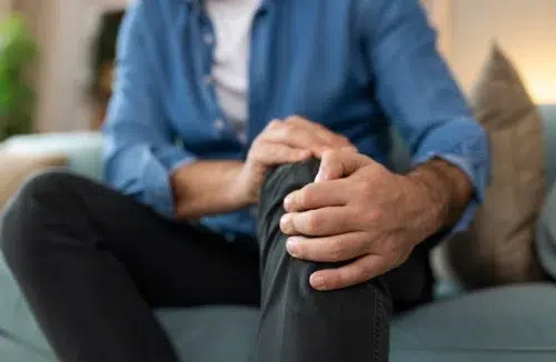 Ein Mann sitzt auf der Couch und hält sein Knie