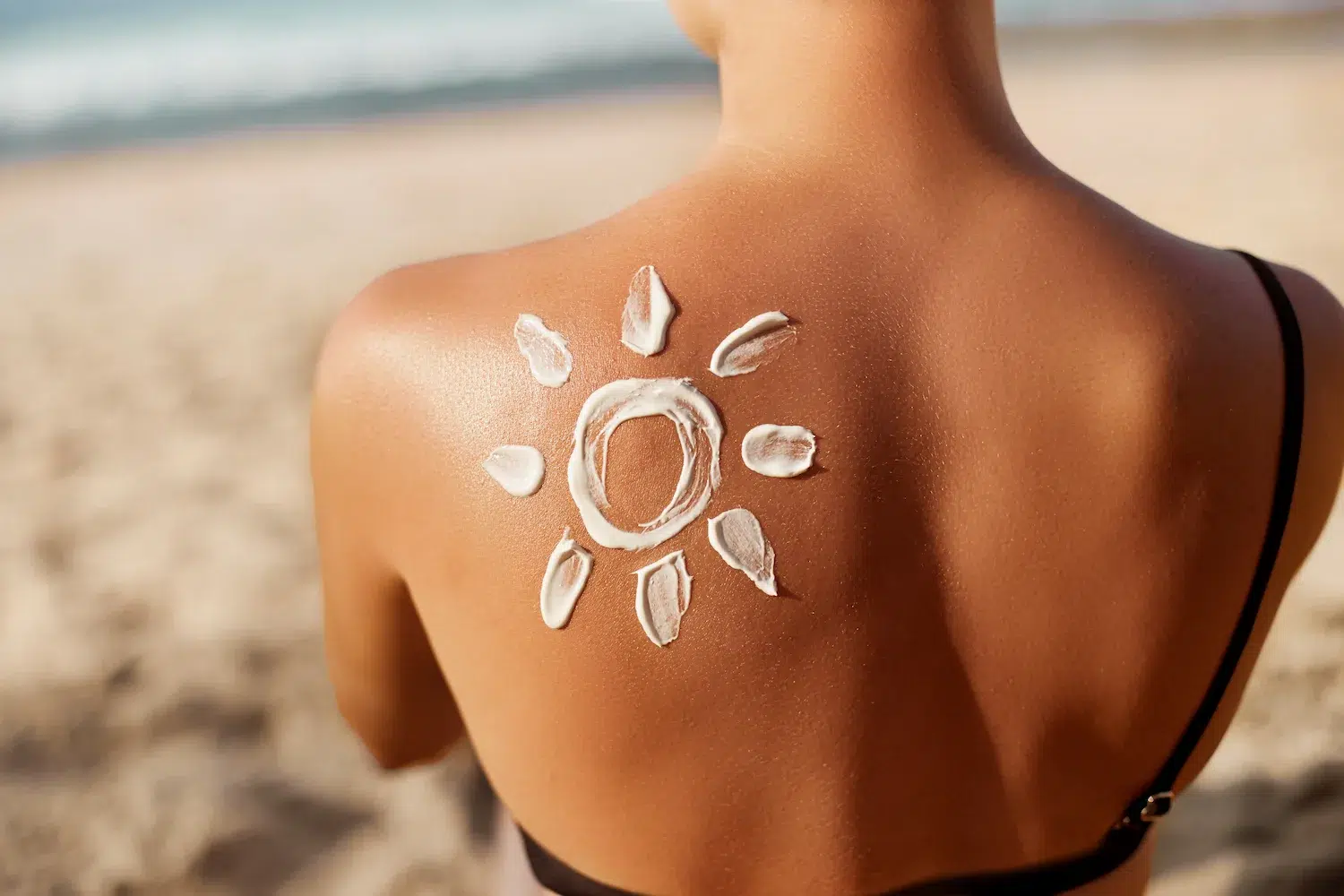Eine Frau am Strand mit einer Sonne aus Sonnencreme auf der Schulter
