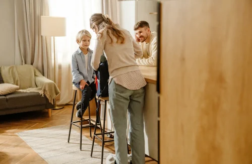 Mutter und Vater packen gemeinsam mit dem Sohn die Schultasche für den Schulstart