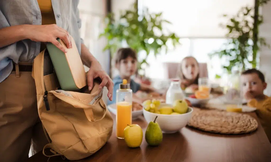 Eine Mutter packt die Jausenbox in den Kinder-Rucksack