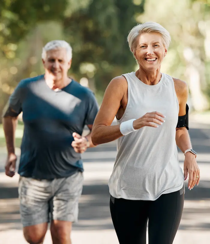 Ein älteres Paar joggt auf einer Straße mit Bäumen